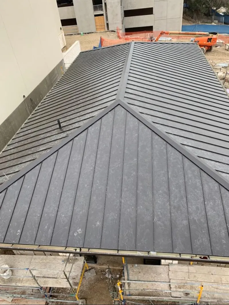 Commercial metal roof construction with crane equipment in Cushing
