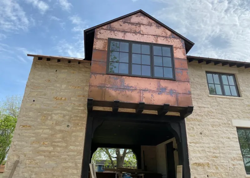 Copper metal panel facade on a stone building for Roof Repair in Cushing